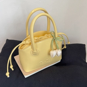 Detail of yellow leather bucket bag with TonTon logo and tulip floral charm