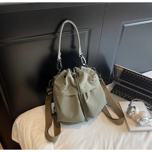 Detail of army green nylon bucket bag featuring drawstring closure and wide fabric strap