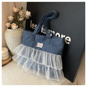 Detail of blue denim tote bag featuring white tulle ruffles and Fashion Bag patch