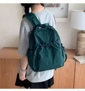 Detail of dark green nylon backpack with drawstring closure and side adjustment buckle