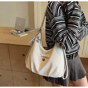 Detail of cream PU leather shoulder bag featuring a cute bow and silver balloon dog charm