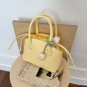 Detail of bright yellow leather bucket bag with white tulip charm and BonBon logo