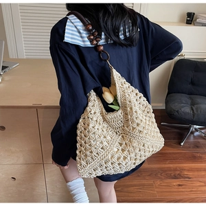 Detail view of woven tote bag with wood bead handles and intricate hollow knit pattern