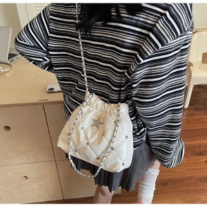 Détail du sac seau blanc matelassé avec motif à losanges et emblème d'étoile en cristal