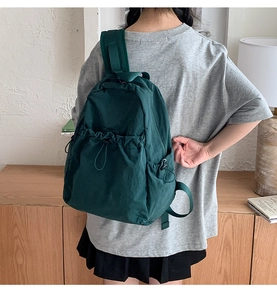 Macro detail of dark green drawstring backpack showing durable texture and side buckles