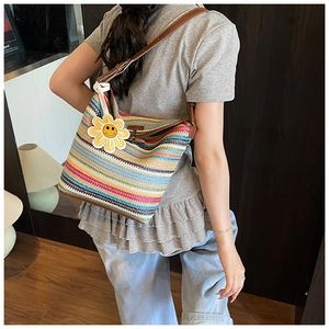 Close-up of colorful striped straw tote bag featuring leather straps and sunflower charm