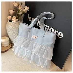 Macro view of light blue denim tote bag with white lace ruffles and Fashion Bag label