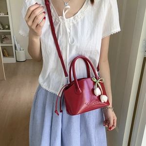 Red patent leather mini shell bag with tulip charm and embossed detail on adjustable strap