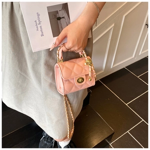 Detailed view of pink quilted handbag featuring gold metal chain and spherical charm