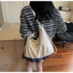 Detail of creamy white pleated shoulder bag with star charm and heart bow accessory