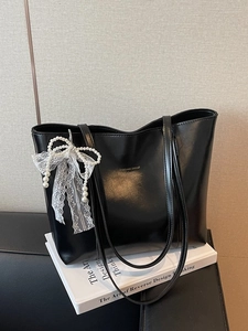 Retro black PU leather tote bag with lace bow and pearl charm on white books
