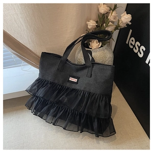 Macro detail of black denim tote bag featuring tulle lace layers and Fashion Bag label