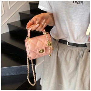 Detail of pink quilted chain bag with gold twist lock on a textured mini handbag