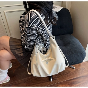 Detail of off-white hobo bag with bow decoration and star charm worn by a model