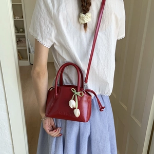 Detail of burgundy glossy bucket bag with tulip charm and elegant embossed lettering