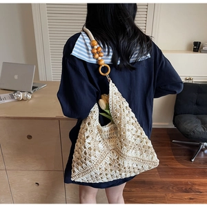 Detailed shot of beige crochet tote bag featuring wooden bead straps and floral accents