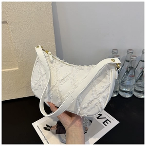 Close-up of white crescent hobo bag featuring tactile fringed texture and gold zipper detail