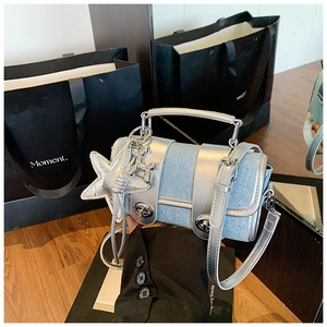 Détail d'un mini sac à main bleu clair texturé avec deux verrous argentés et breloque