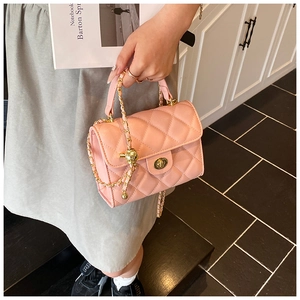 Detailed view of pink quilted handbag featuring gold twist lock and ball chain strap