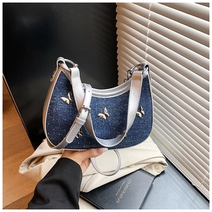 Dettaglio di una borsa a tracolla in denim blu con farfalle dorate e cinturini argento