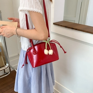 Detail of red patent leather bucket bag with white tulip charms and Tonton embossed logo
