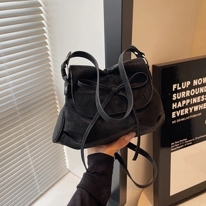 Detail of a black matte leather bow shoulder bag with silver hardware and soft texture