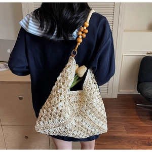 Detail of hollow woven tote bag with unique round wooden bead shoulder strap and floral accent