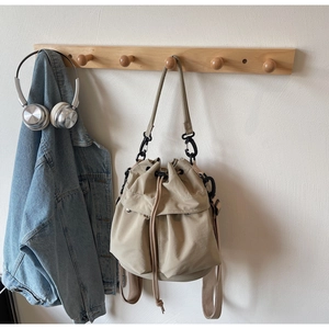Detail of khaki drawstring bucket bag featuring multiple utility pockets and metal hardware
