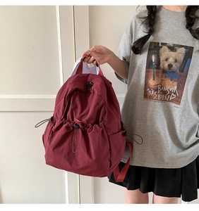 Detail of burgundy drawstring backpack featuring durable water-resistant fabric and side pocket