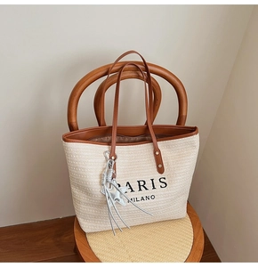 Detail of rainbow straw tote bag with brown PU handles and a silver star tassel charm