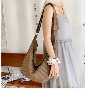 Braune karierte Hobo-Tasche in Lifestyle-Szene mit verstellbarem breitem Schultergurt