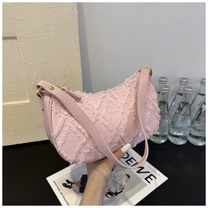 Pink denim baguette bag featuring distressed frayed edges and a smooth leather strap