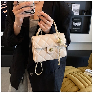 Close-up of beige quilted chain bag featuring gold ball adjuster and metallic twist lock