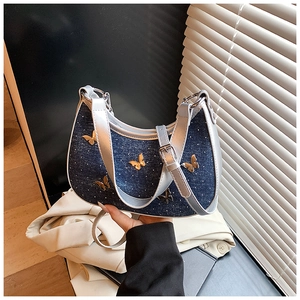 Dettaglio borsa a mezzaluna in denim blu con finiture in pelle argento e farfalle oro