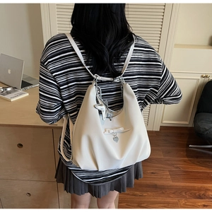 Detailed view of white pleated PU leather backpack with bow and silver star pendant charm