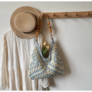 Detail of hand-woven crochet tote with light blue patterns and wooden bead handles