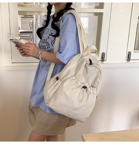 Close-up of cream drawstring backpack showing side view capacity and multiple storage pockets
