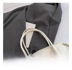 Dettaglio borsa tote in pelle bianca con trama litchi e comodi manici a mano