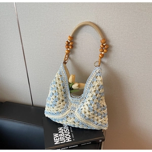 Detailed close-up of woven tote bag featuring light blue patterns and wooden bead handle