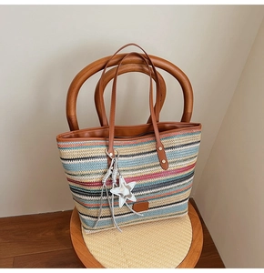 Detail showing colorful woven straw tote with leather handles and star charm on a chair