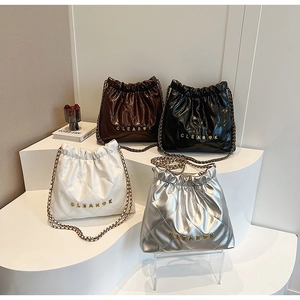 Close-up of quilted bucket bags in brown, black, white, and silver with chain straps
