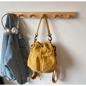Detail of yellow nylon bucket bag showing drawstring closure and outdoor casual style
