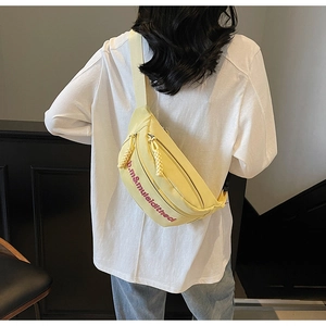 Détail du sac bandoulière jaune avec broderie violette et tirette de zip tressée