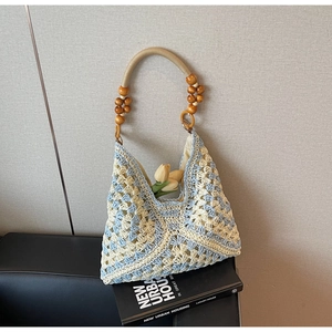 Detail of blue and white crochet tote bag with wooden bead handle and hollow-out pattern