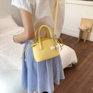 Detail of yellow matte leather bucket bag with TonTon logo and tulip charm on a model