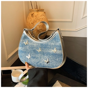 Dettaglio borsa hobo in denim blu con farfalle metalliche 3D e tracolla argento
