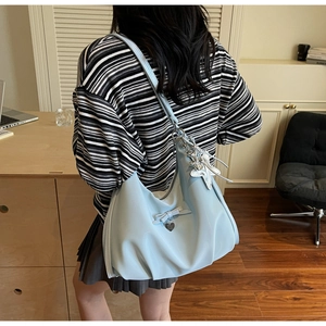 Light blue slouchy shoulder bag with silver star and bow charms worn by model