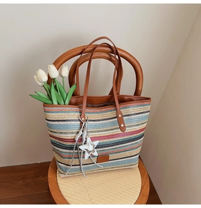 Detail of colorful woven straw tote bag with brown leather handles and star charm