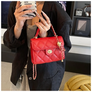 Detail of red quilted crossbody bag with gold twist lock and leather-threaded chain strap