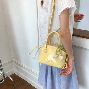 Detail of yellow shell-shaped crossbody bag with tulip charm and embossed logo